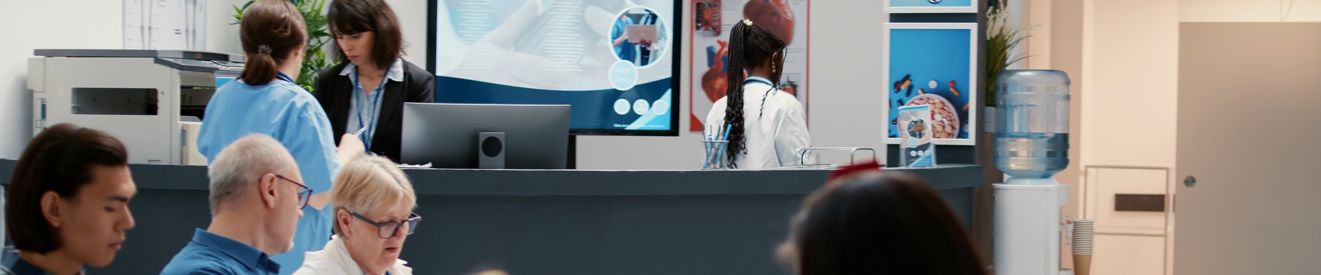 Mostrador de admisión de un centro de salud con pacientes esperando