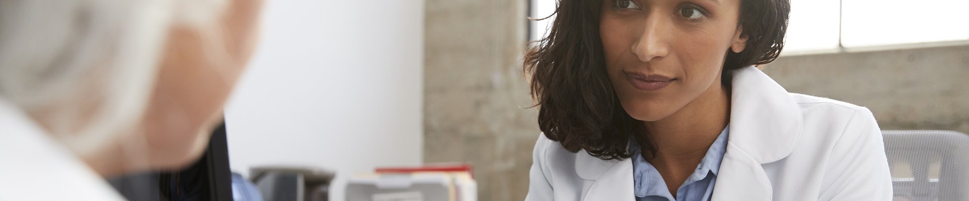 Médica de familia escuchando a un paciente durante la consulta
